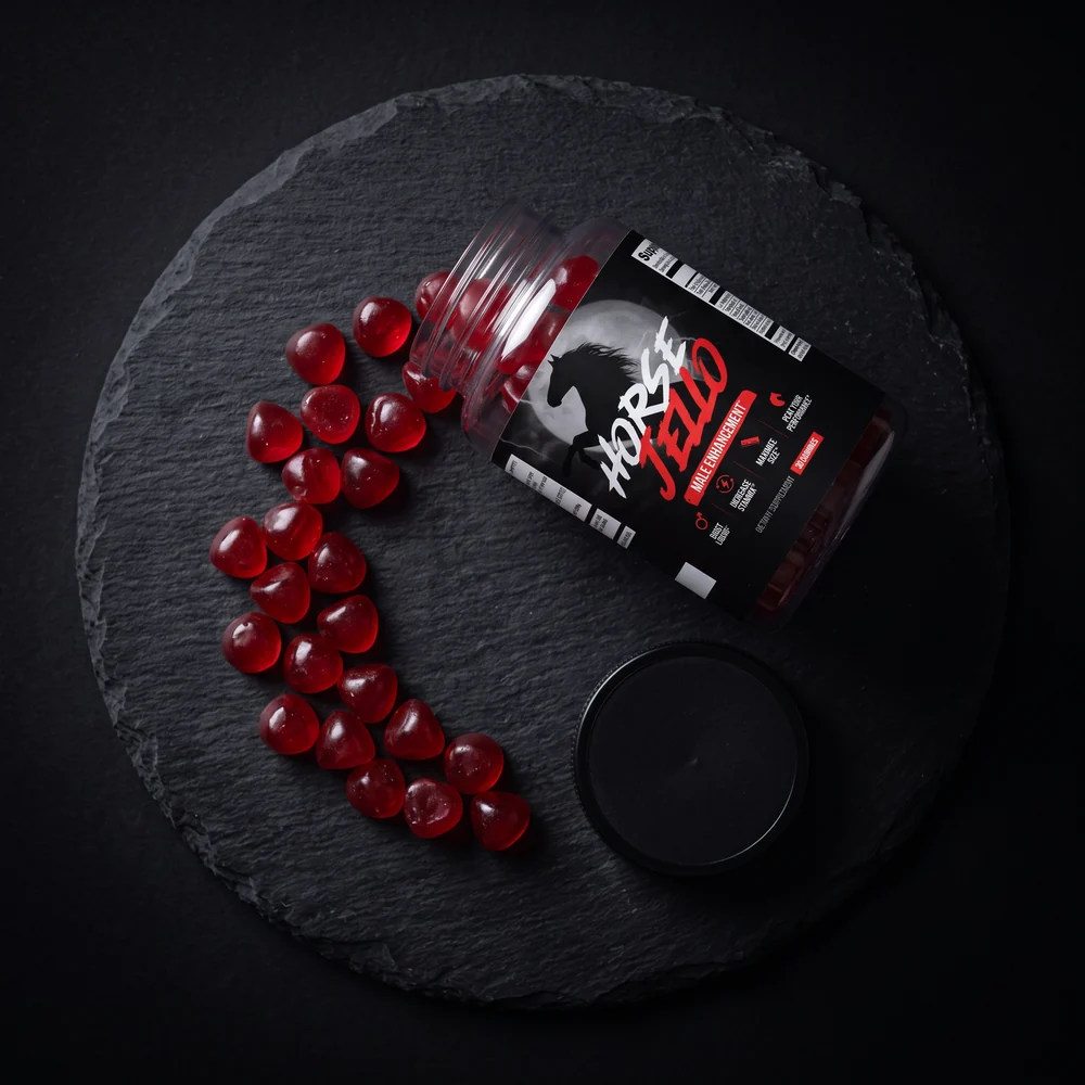 Horse Jello® jar tipped over with red gummies on slate